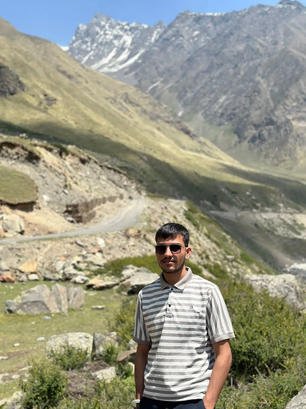 Kulwant standing above a green switchback road near Batal