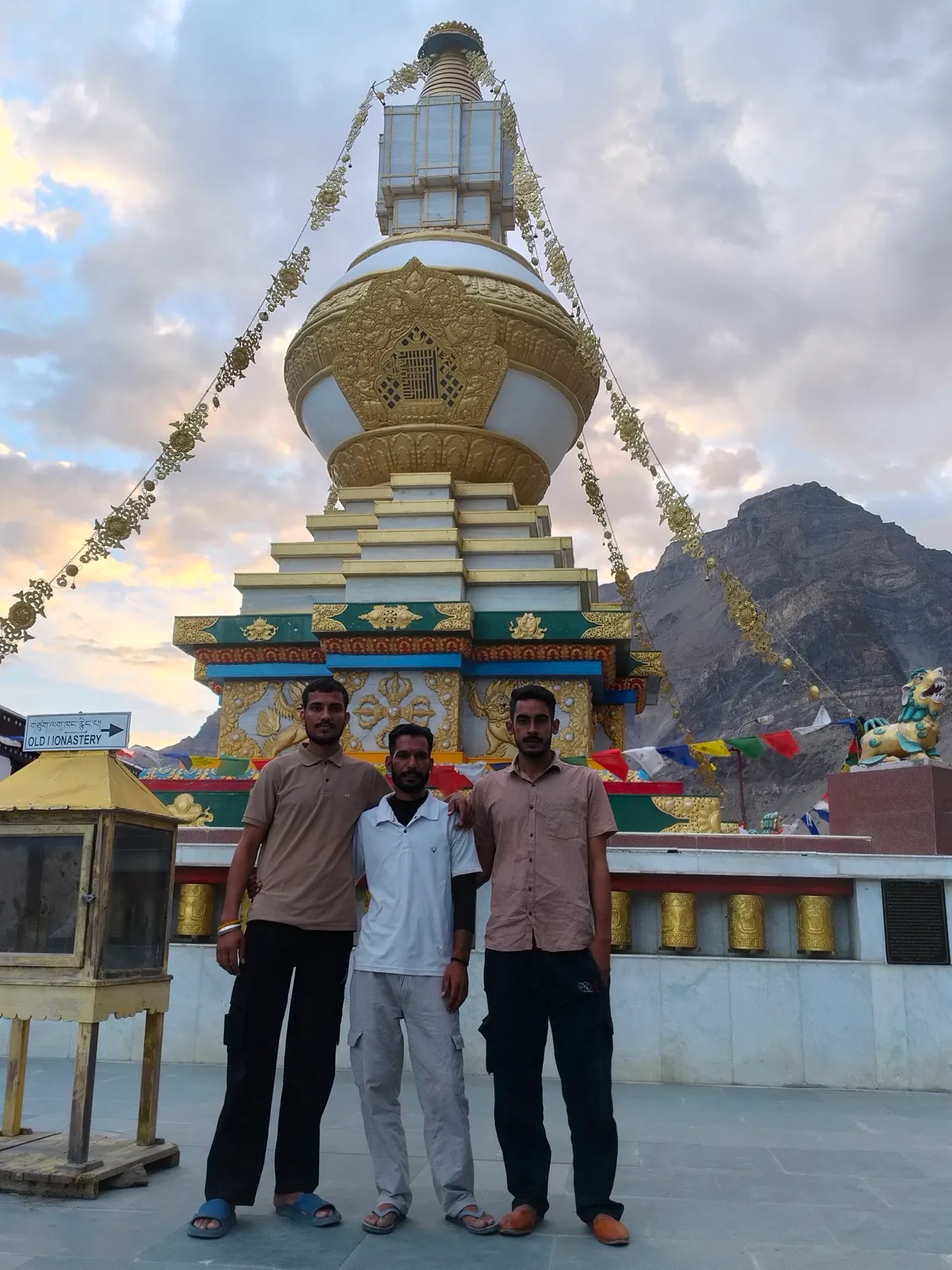 Kulwant with two companions in front of a large gilded stupa near an old monastery