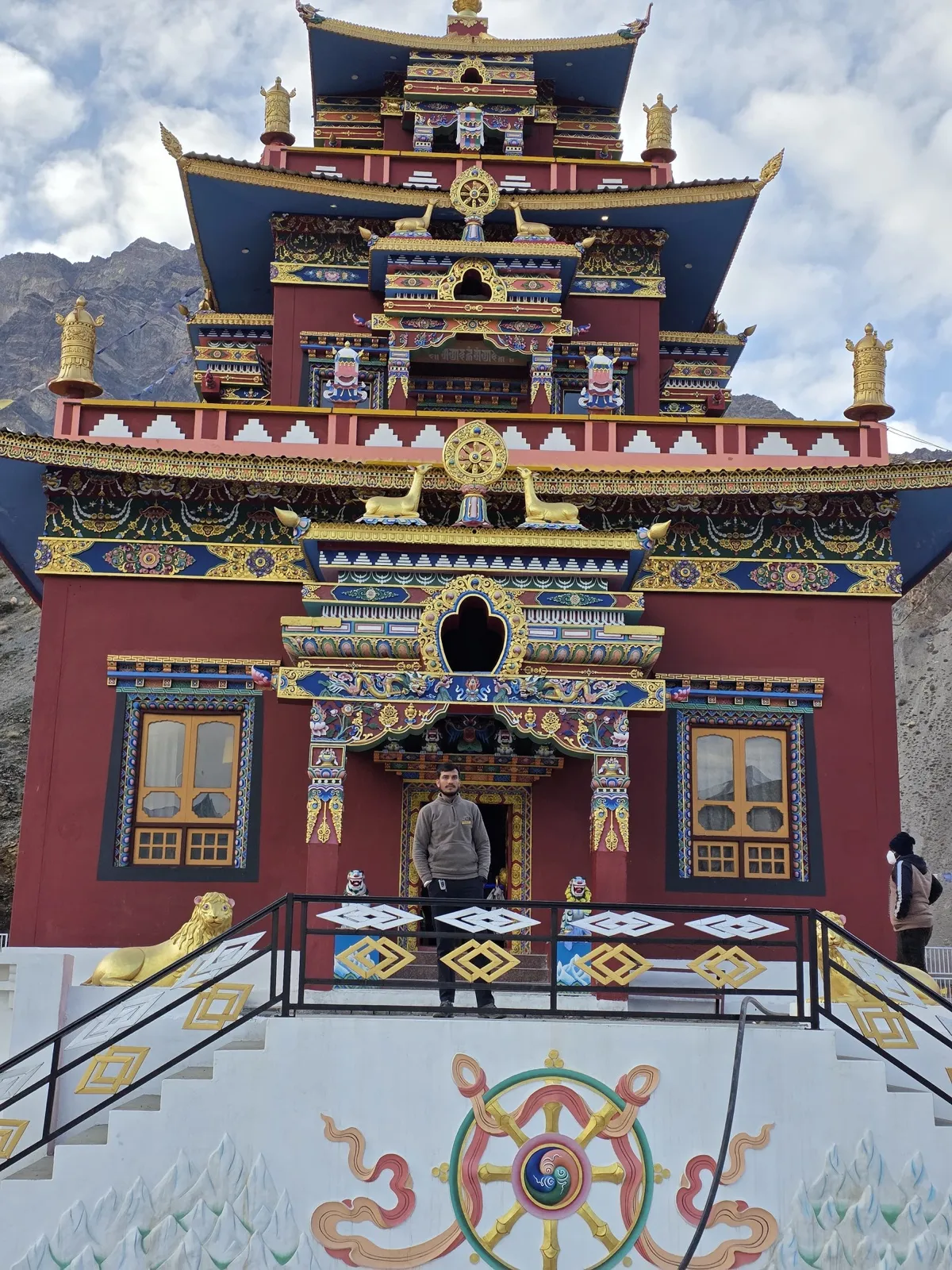 Kulwant standing at the entrance of a red and gold monastery