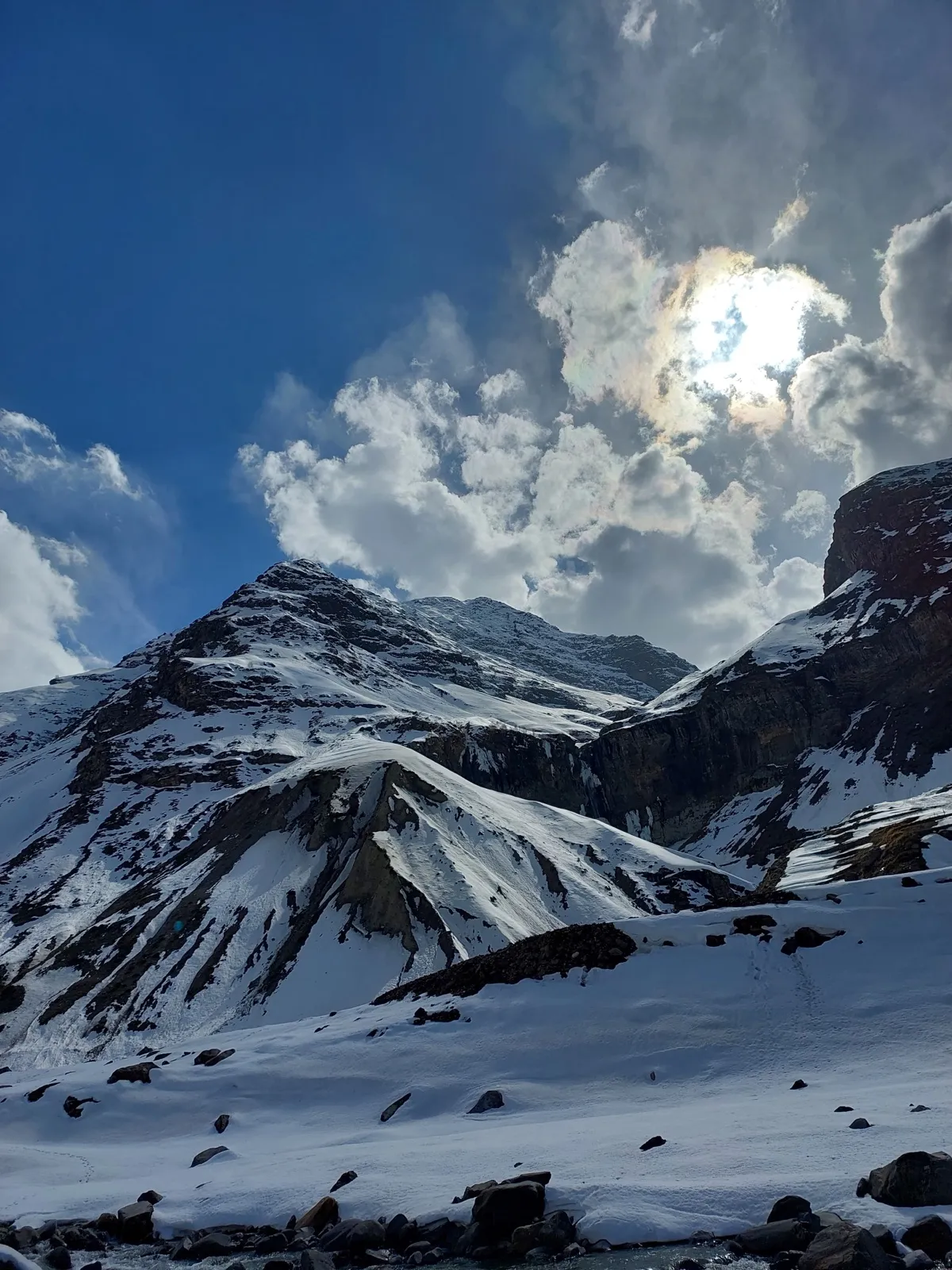 A snow-covered peak with the sun breaking through clouds above