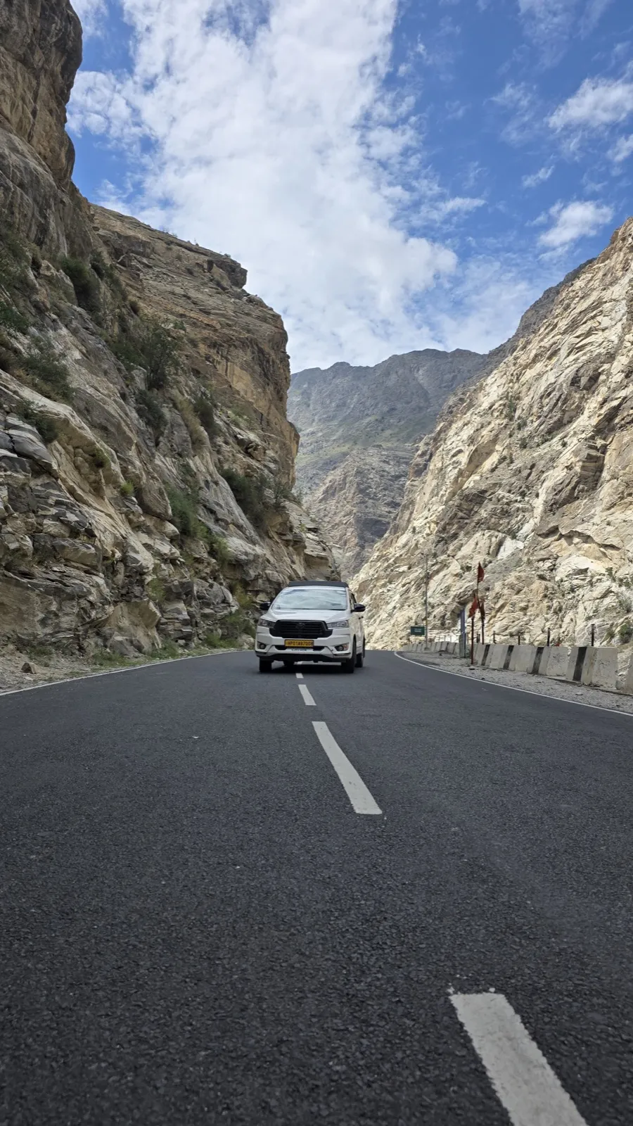 A white SUV on a mountain road cutting through a rock gorge