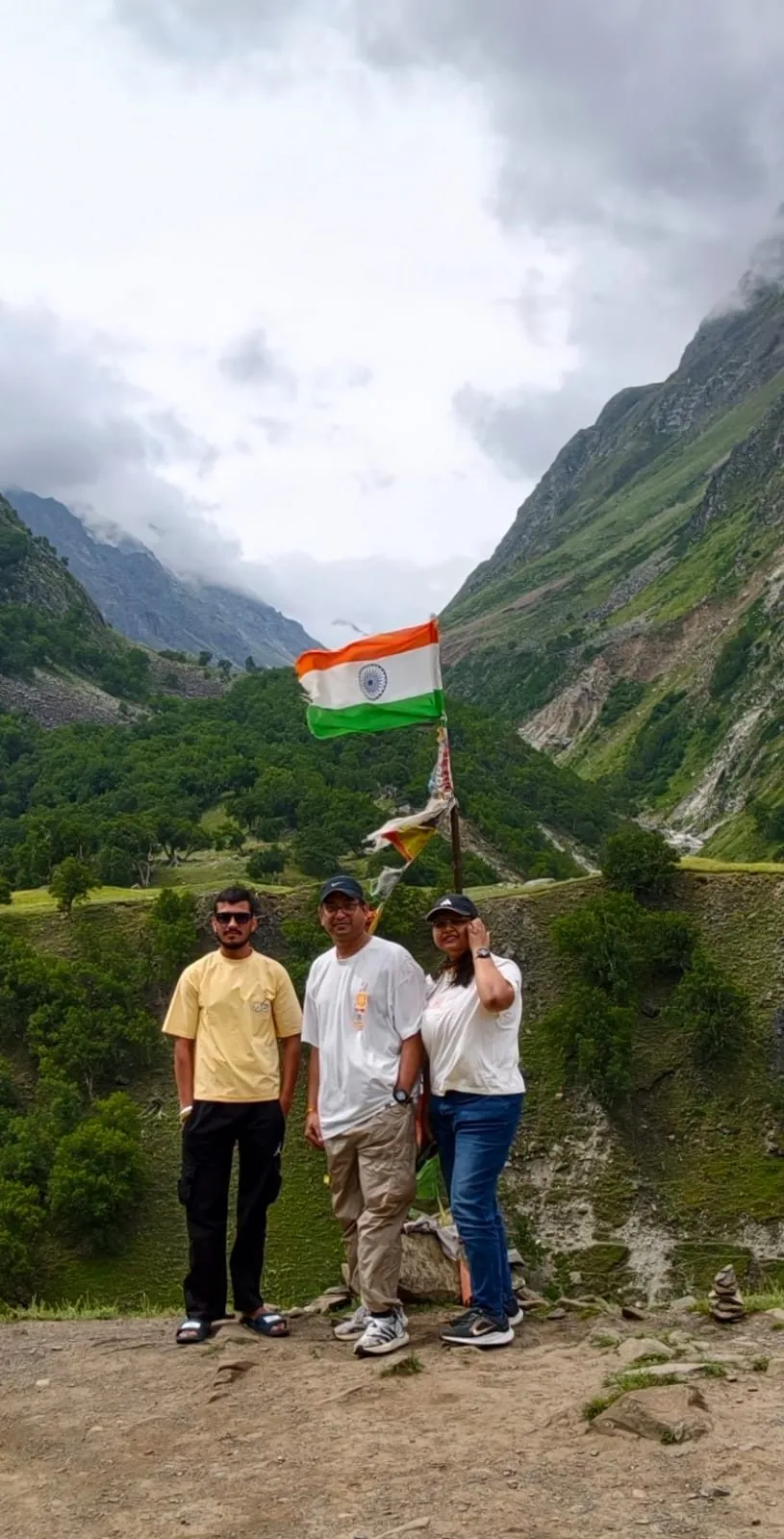 Three travelers at a viewpoint near Chitkul, holding the Indian tricolor