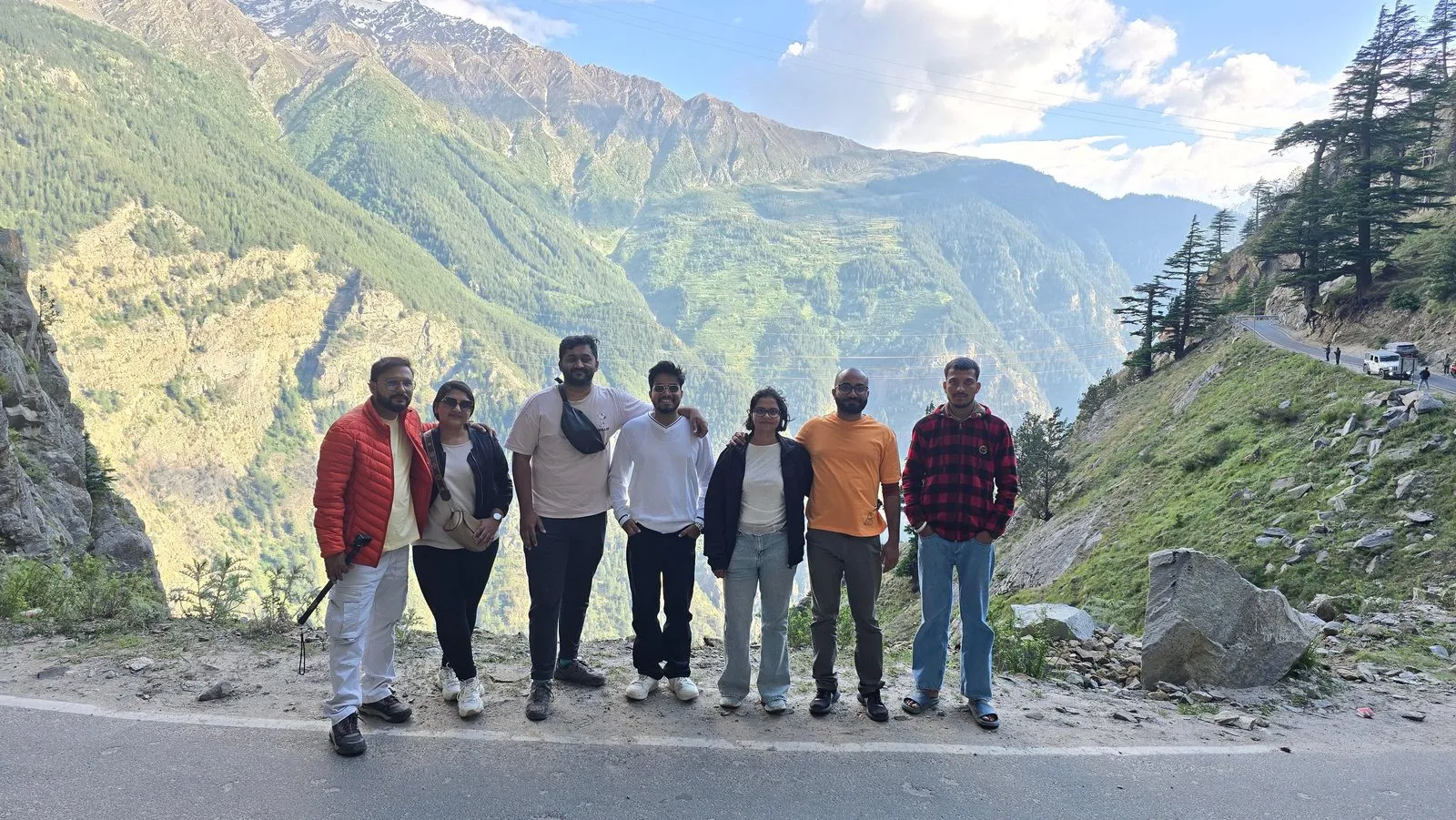 Travelers together on a mountain road overlooking a green valley
