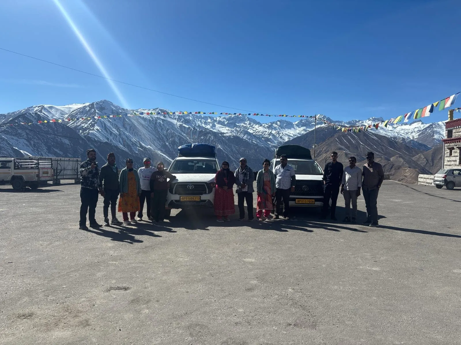 A group of travelers and their vehicles at Nako, beneath prayer flags