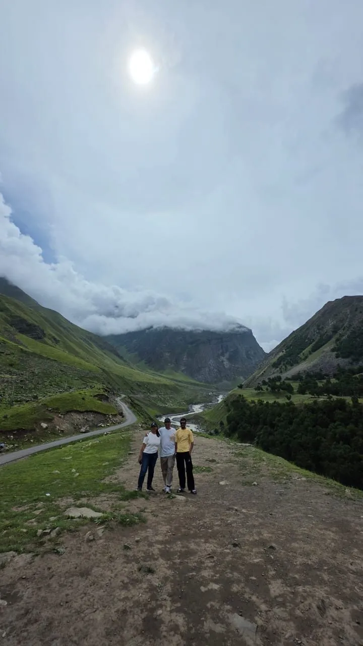 A group of travelers facing the cloud-filled valley above Chitkul